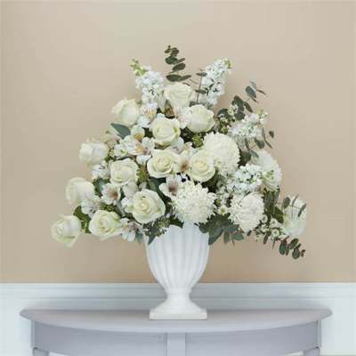 White rose and chrysanthemum arrangement in a white urn vase