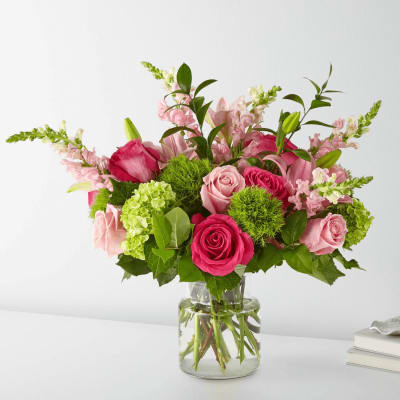 Pink roses and lilies arranged in a clear glass vase