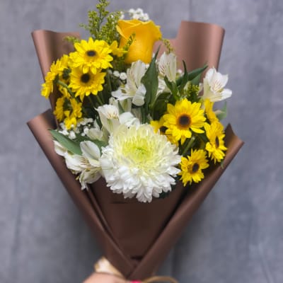 Bouquet of yellow and white flowers wrapped in brown paper