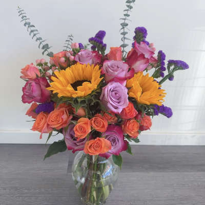 Mixed bouquet of roses and sunflowers in a clear glass vase