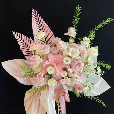 Pink and white floral arrangement with ribbon on tall gold stands