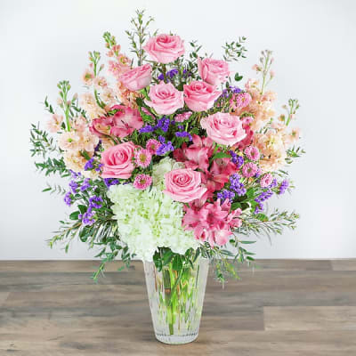 Pink roses and mixed flowers in a clear glass vase
