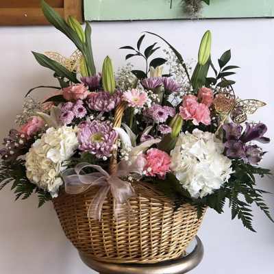 Basket arrangement of pink, white, and purple flowers with lilies and hydrangeas