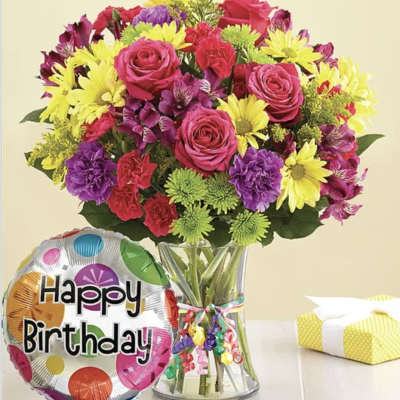 Mixed bouquet in a glass vase with a birthday balloon beside it