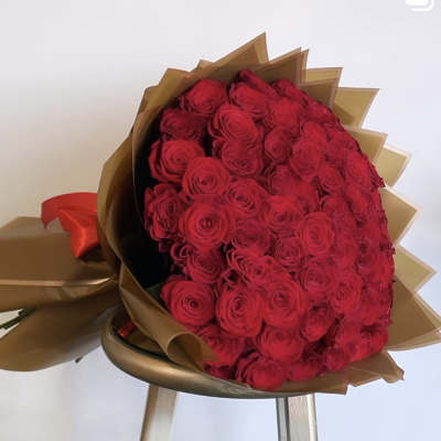 Large bouquet of red roses wrapped in brown paper with a red ribbon