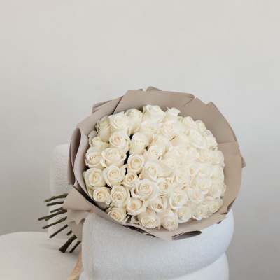 Bouquet of white roses wrapped in beige paper