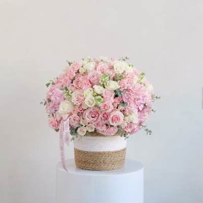 Large pink and white rose arrangement in a woven basket