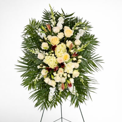 Tall standing spray of ivory roses and hydrangeas with palm fronds on a metal easel