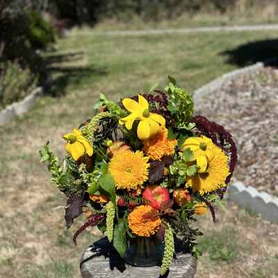 Bright mixed bouquet in a dark vase with yellow and orange blooms