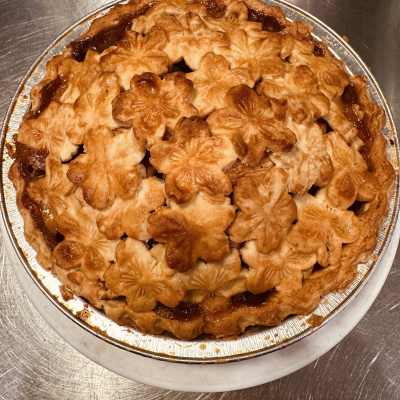 A baked pie with a decorative flower-shaped crust in a foil pan