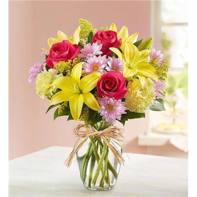 Bouquet of pink roses and yellow lilies in a clear glass vase