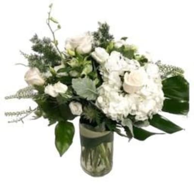 White roses and hydrangeas in a glass vase with greenery