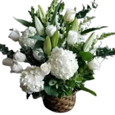 White lilies and hydrangeas arranged in a woven basket