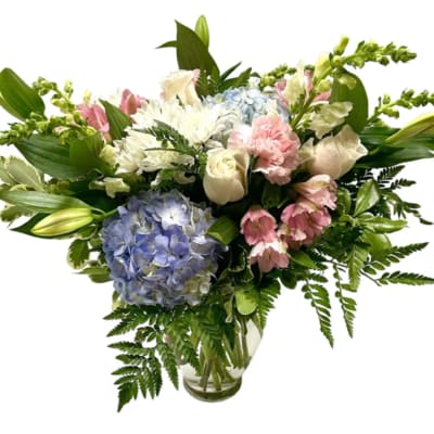 Pastel mixed bouquet in a clear glass vase with hydrangeas, roses, lilies, and carnations