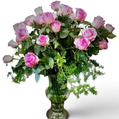 Pink roses arranged in a clear glass vase with trailing greenery