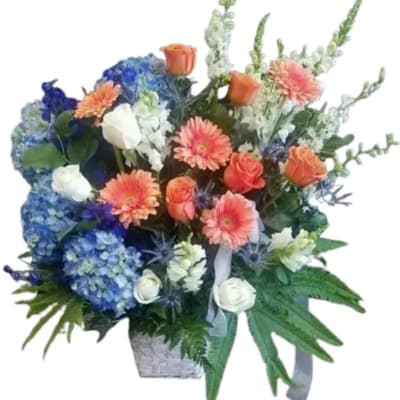 Mixed bouquet with blue hydrangeas, orange roses, and peach gerbera daisies in a basket