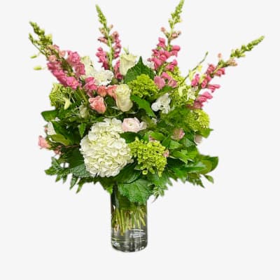 Tall mixed bouquet of pink and white flowers in a clear glass vase