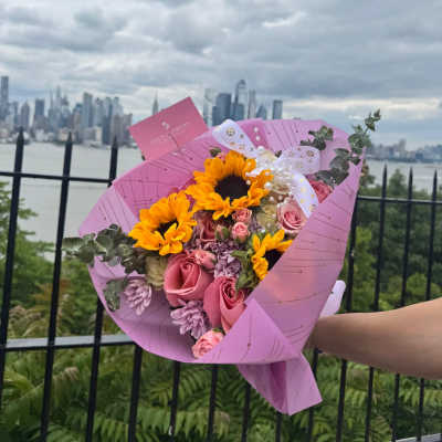 Sunset glow ( 12 light pink roses with mini roses, 3 sunflowers, and accompanied by greenery and eucalyptus.