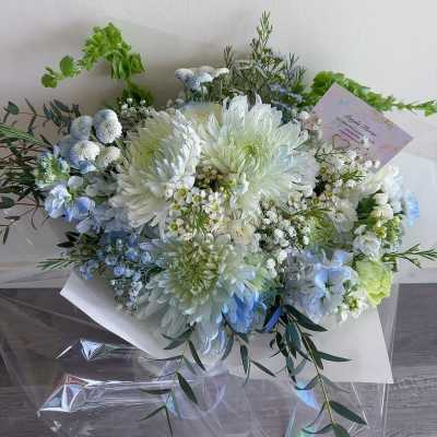 Bouquet of white and pale blue flowers wrapped in white paper