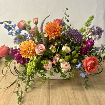 Mixed bouquet in a white rectangular vase with orange, pink, purple, and blue flowers