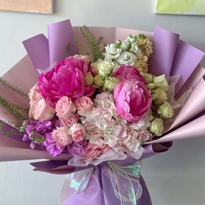 Bouquet of pink and white flowers wrapped in lavender paper