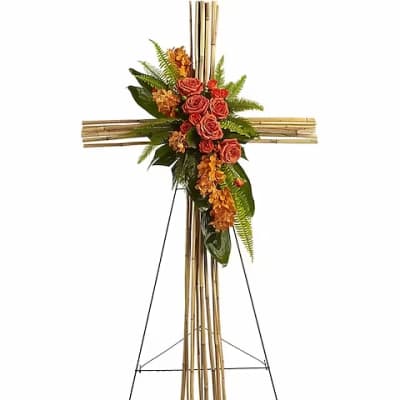 Standing floral cross with orange roses and greenery on an easel