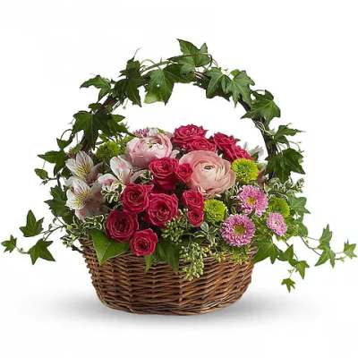 Basket of pink roses and mixed flowers with ivy arching over it