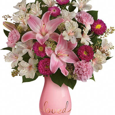 Pink lilies and mixed blooms in a pink vase with the word loved
