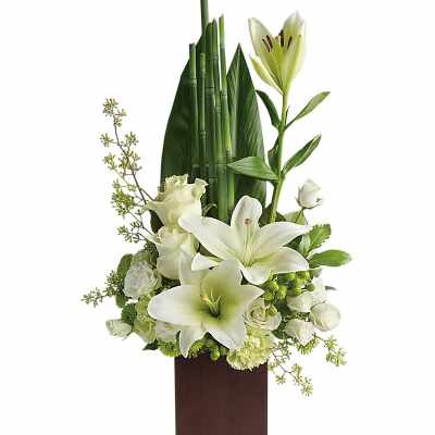 White lilies and roses arranged in a tall brown vase