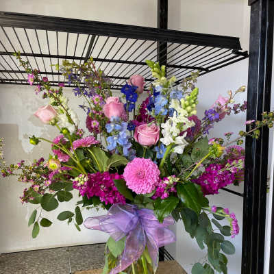 Large mixed bouquet in a glass vase with pink, purple, blue, and white flowers