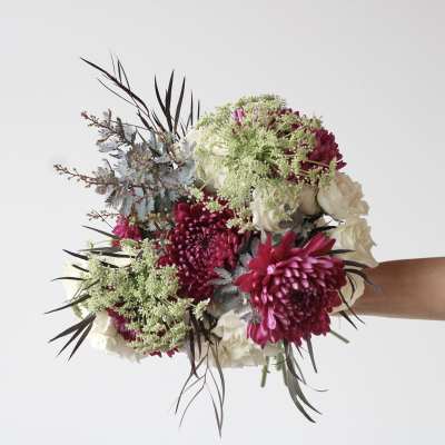 Handheld bouquet of magenta and white flowers with dark foliage