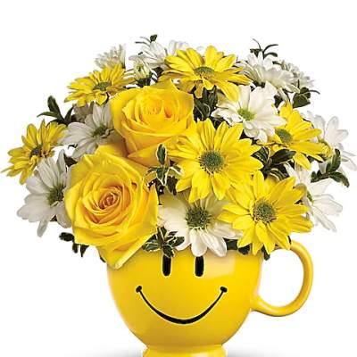 Yellow and white flowers arranged in a smiley-face mug