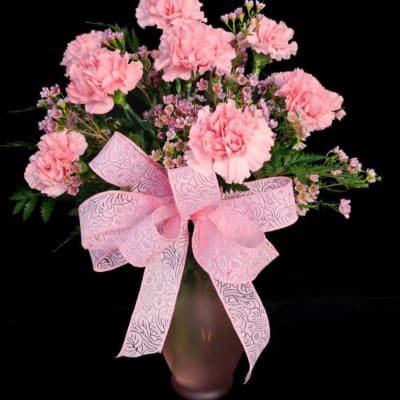 Pink carnations in a vase with a large pink bow