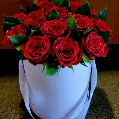 Red roses arranged in a white round box with ribbon handles