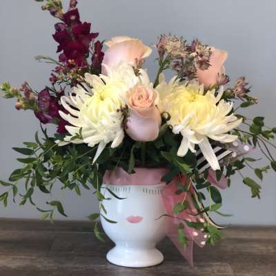 Bouquet of white and blush flowers in a white face vase