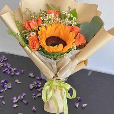Bouquet with a sunflower, orange roses, and small white daisies in kraft paper