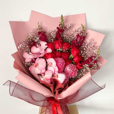 Bouquet of red roses and pink orchids wrapped in pink paper