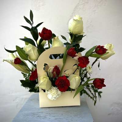 Red and white tulips with carnations in a cream gift bag