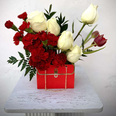 Red carnations and white roses in a red gift box