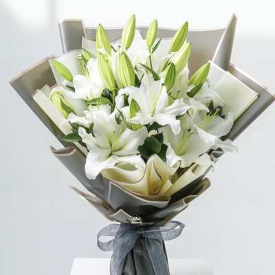 Bouquet of white lilies wrapped in gray paper with a ribbon