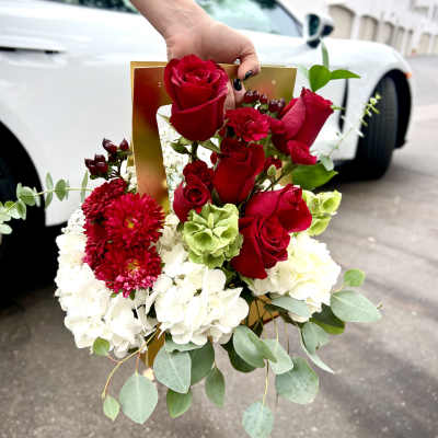 Hand holding a bouquet of red roses and white hydrangeas
