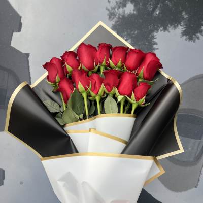 Bouquet of red roses wrapped in black and white paper with a pink ribbon
