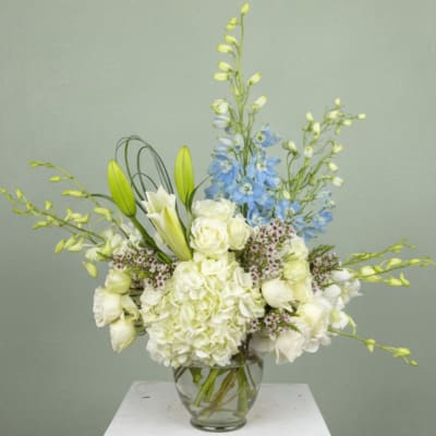 White and blue floral arrangement in a clear glass vase
