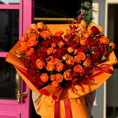 Large bouquet of red and orange roses wrapped in orange paper