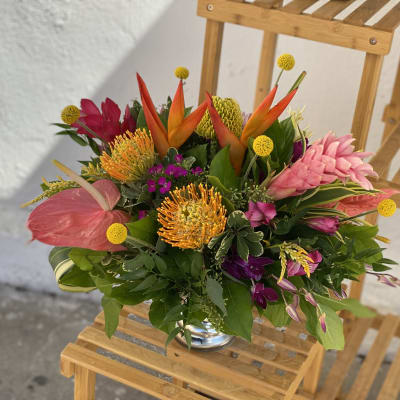 Tropical bouquet with pink, orange, and yellow flowers in a glass vase