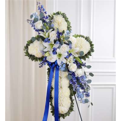 White floral cross arrangement with blue flowers and a blue ribbon