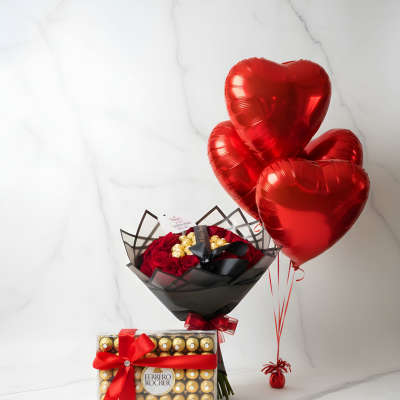 Red heart balloons beside a bouquet of red roses and a Ferrero Rocher gift box