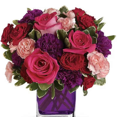 Bouquet of pink, red, and purple flowers in a purple glass vase
