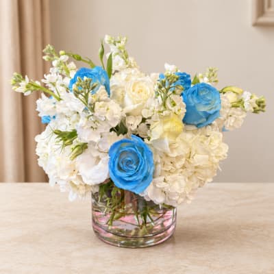 White and blue flower arrangement in a clear glass vase