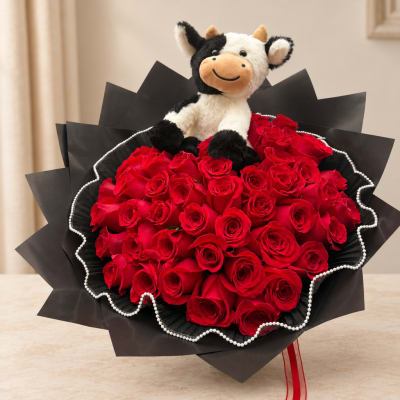 Bouquet of red roses with a plush cow topper